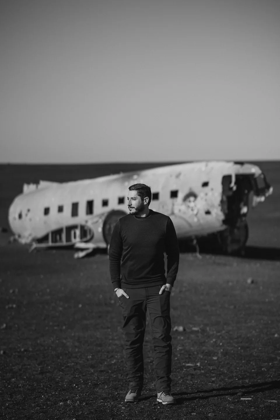Retrato en blanco y negro de David Bresó ante un avión abandonado.