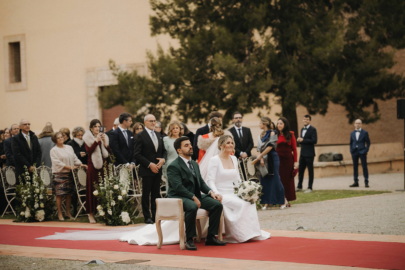 Germán y Carla sentados durante su ceremonia en el jardín. Fotografía de David Bresó.