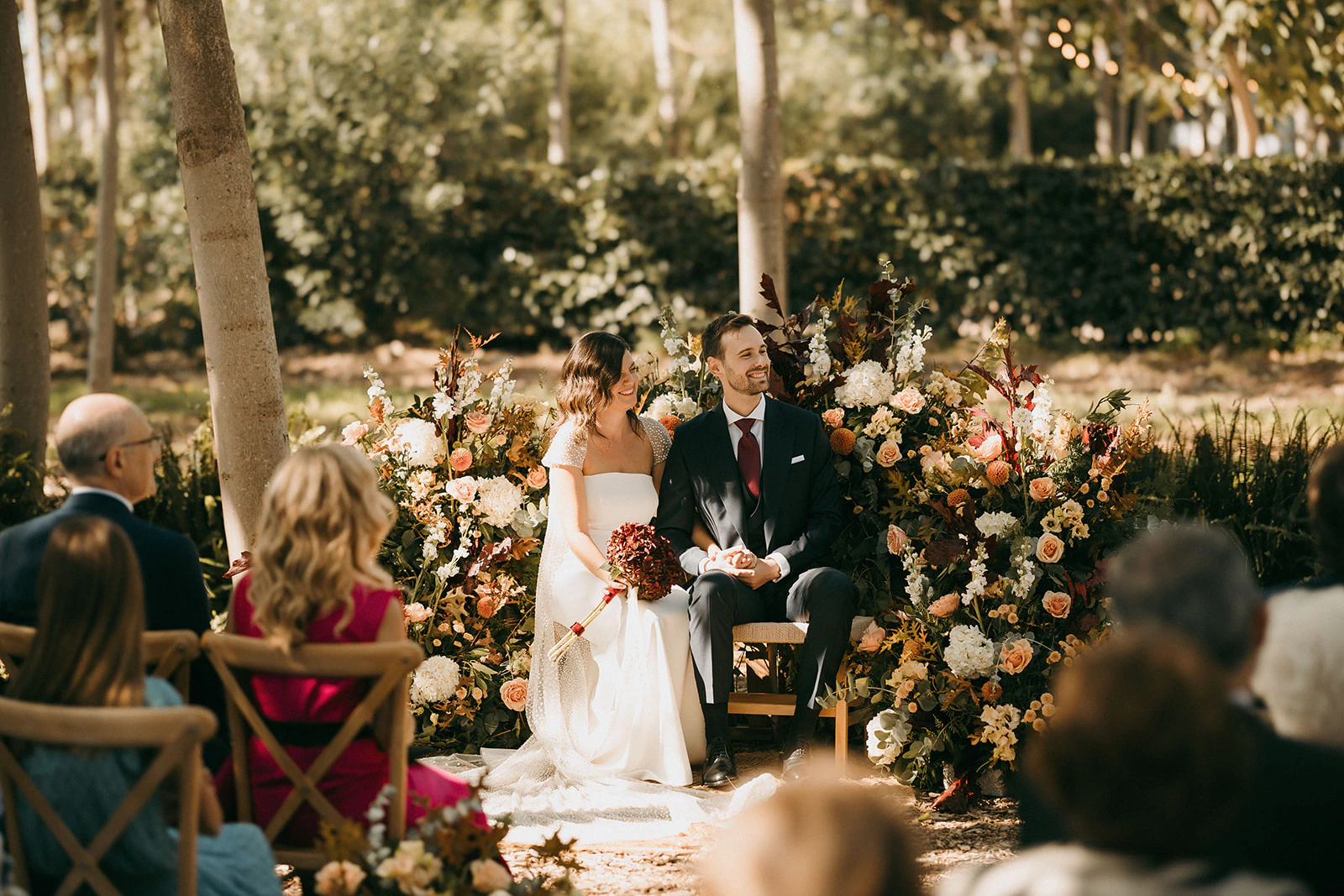 Sergio y Claudia durante la ceremonia entre árboles y flores. Fotografía de David Bresó.