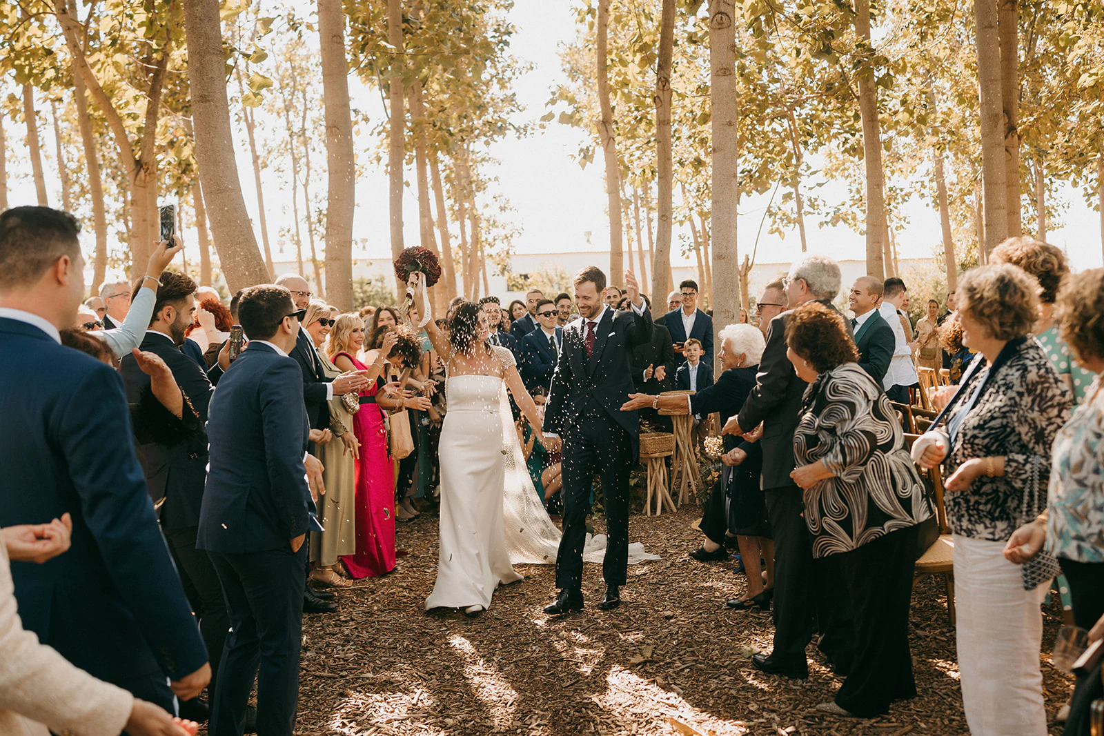 La pareja sale de la ceremonia celebrando con sus invitados. Fotografía de David Bresó.