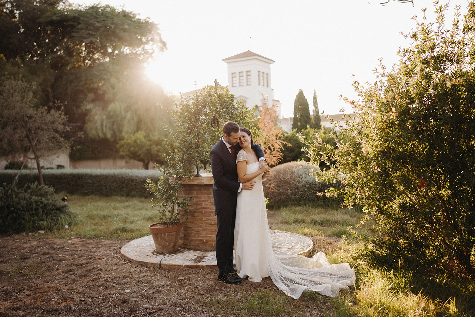 Sergio y Claudia se abrazan junto a la masía al atardecer. Fotografía de David Bresó.